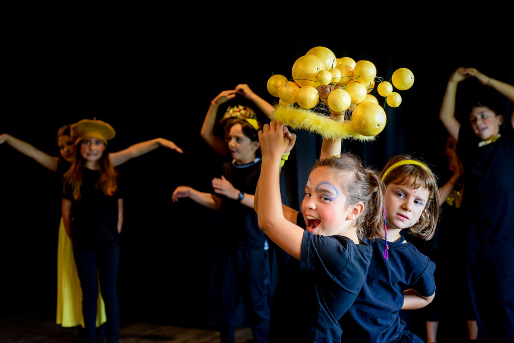 Allievi del corso di teatro per Bambini di SpazioMio giocano con copricapo con pianeti giallo
