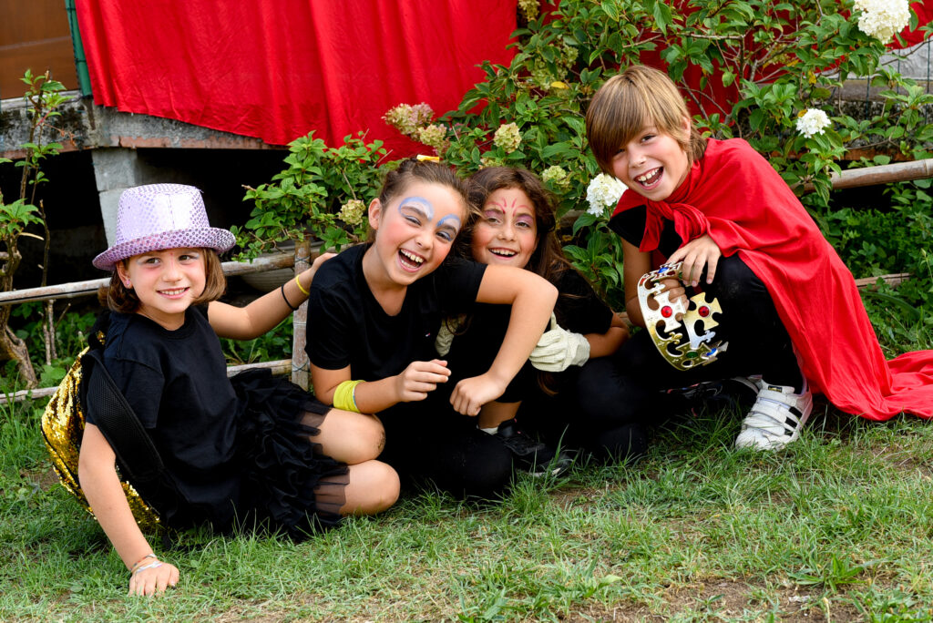 Quattro bambini sorridenti con cappelli e vestiti di scena che partecipano ai Centri Estivi di SpazioMio a Verona